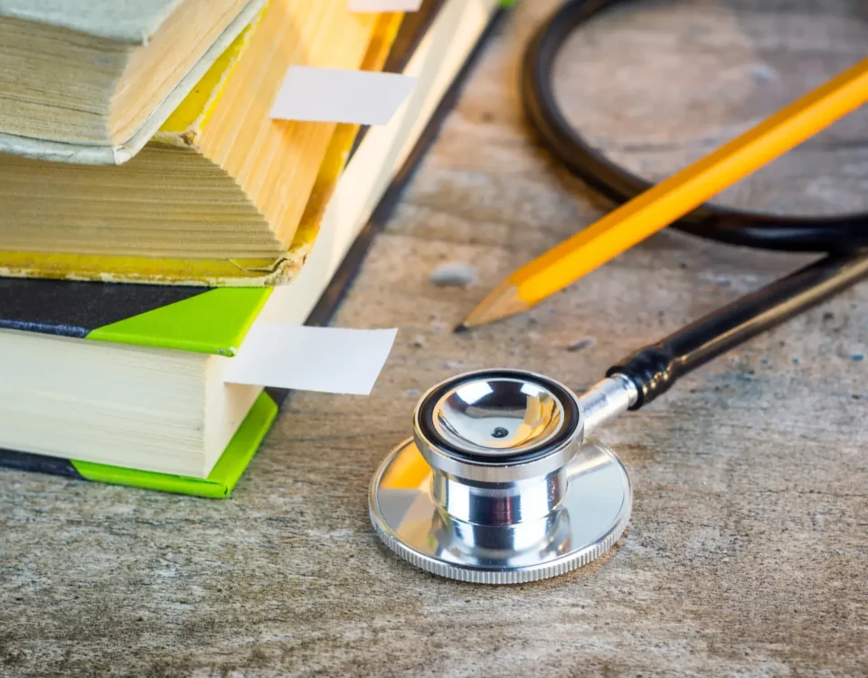 Stethoscope next to text books and pencil