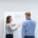 Man and woman discussing material on a whiteboard